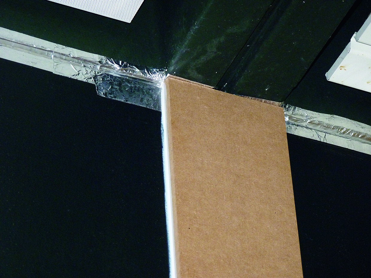 Caulk encapsulated by aluminium tape; on the wall part covered by a wooden panel.